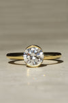 Gold ring with a large diamond on a beige background