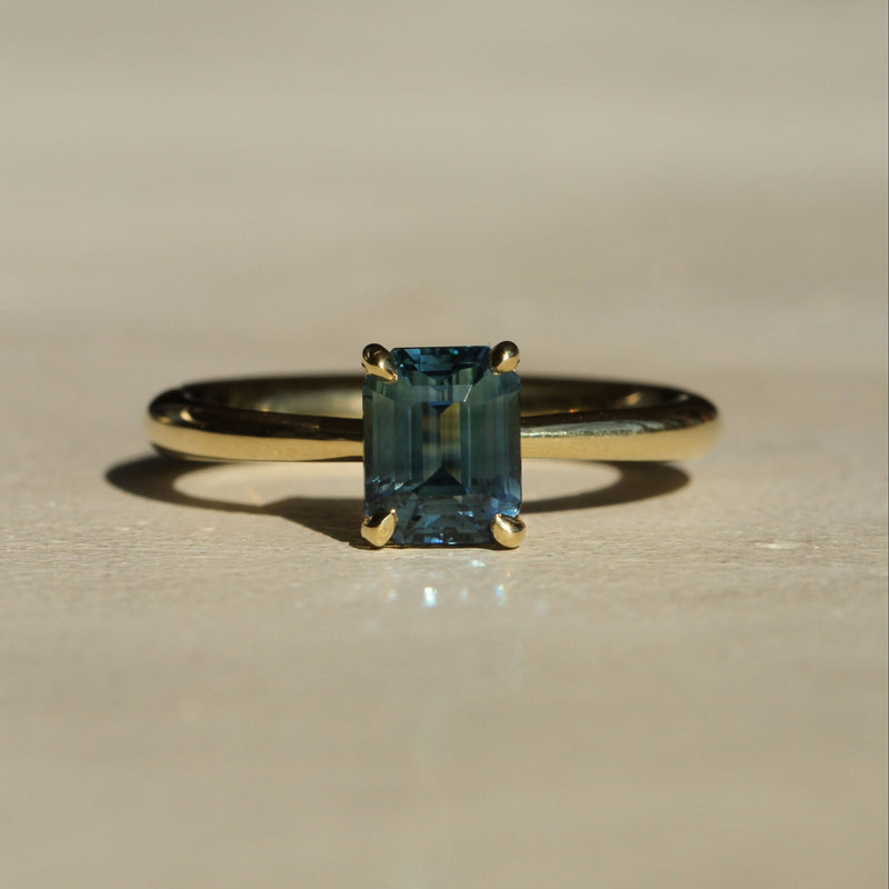 Sophie Hughes Four-Prong Solitaire in 18K Yellow Gold featuring a 1-ct Emerald Cut teal Montana Sapphire