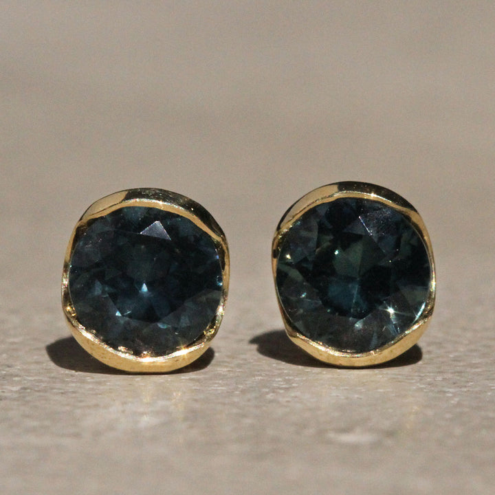 Sophie Hughes Poppy Bezel Montana Sapphire Studs in 18k Yellow Gold featuring a pair of 4.75mm Dark Teal Round Montana Sapphires