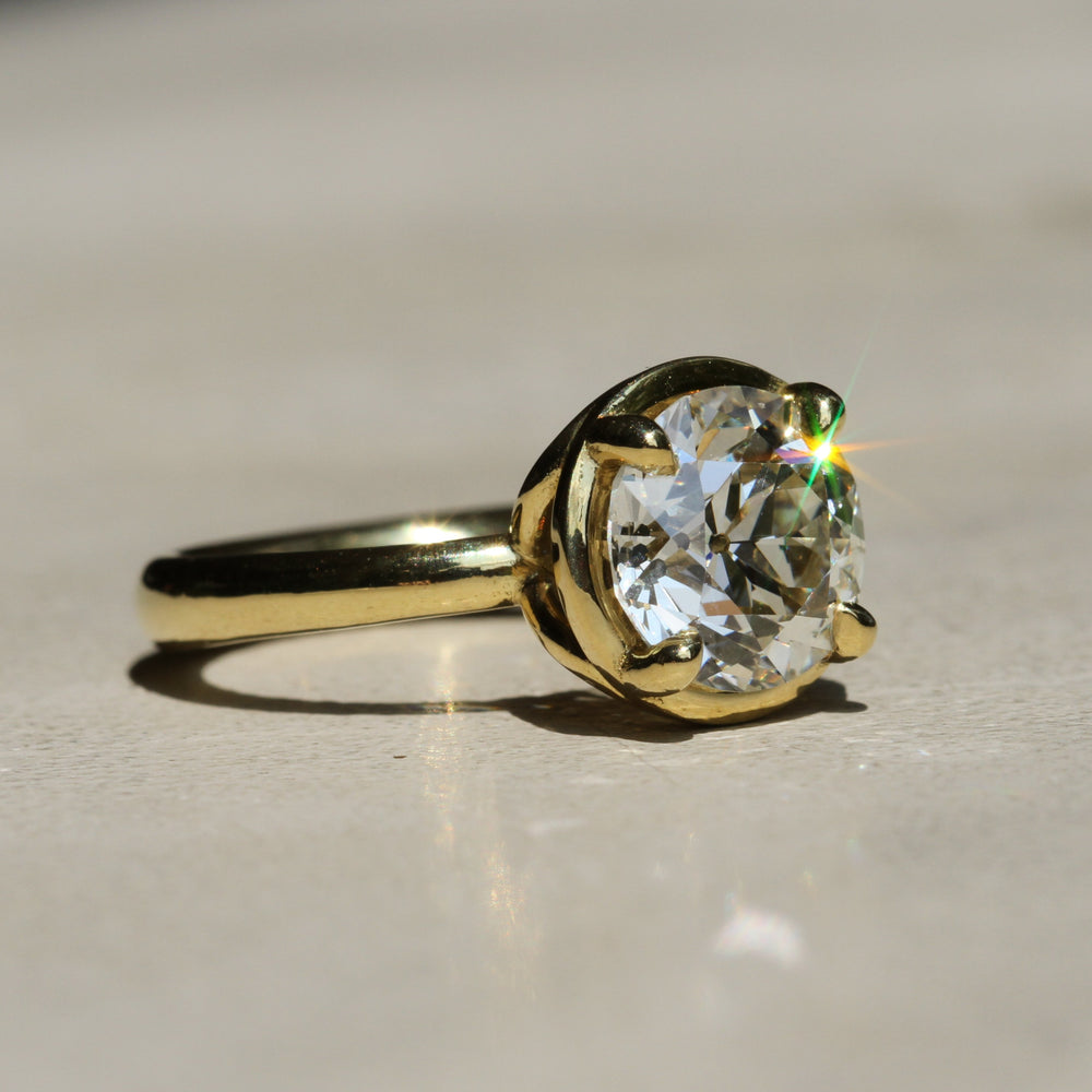 Sophie Hughes Theia Prong Solitaire in 18K Yellow Gold featuring a 2.5-ct Antique Old European cut diamond from an angle