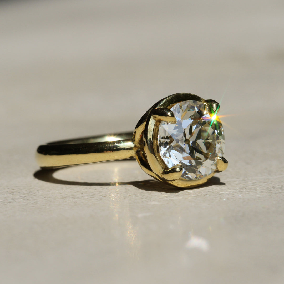 Sophie Hughes Theia Prong Solitaire in 18K Yellow Gold featuring a 2.5-ct Antique Old European cut diamond from an angle