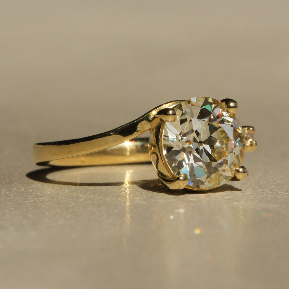 Sophie Hughes Crest Prong Ring in 18K Yellow Gold featuring a 2.5-ct Antique Old European cut diamond with 5 Champagne melee diamonds at a slight angle
