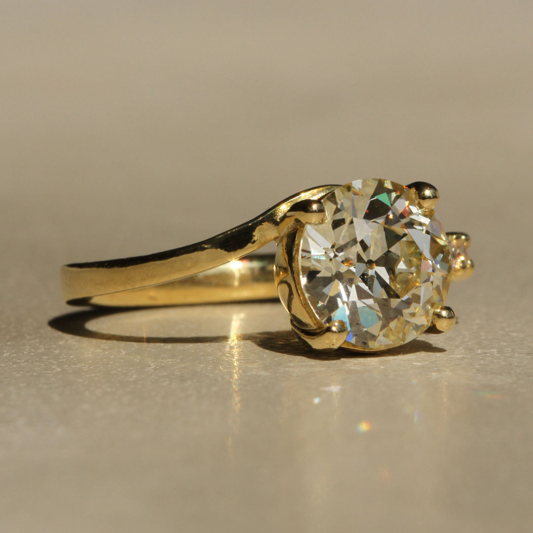 Sophie Hughes Crest Prong Ring in 18K Yellow Gold featuring a 2.5-ct Antique Old European cut diamond with 5 Champagne melee diamonds at a slight angle