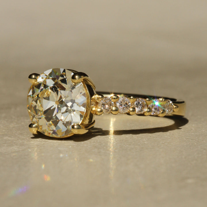 Sophie Hughes Crest Prong Ring in 18K Yellow Gold featuring a 2.5-ct Antique Old European cut diamond with 5 Champagne melee diamonds at a slight angle