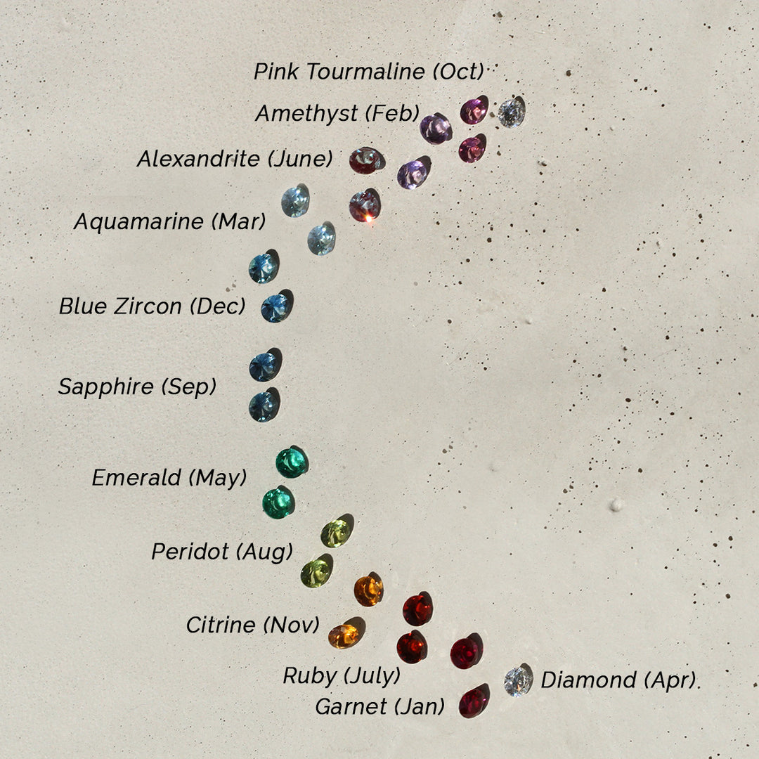 A selection of gemstone studs, each featuring a different colored gemstone, displayed against a neutral background.