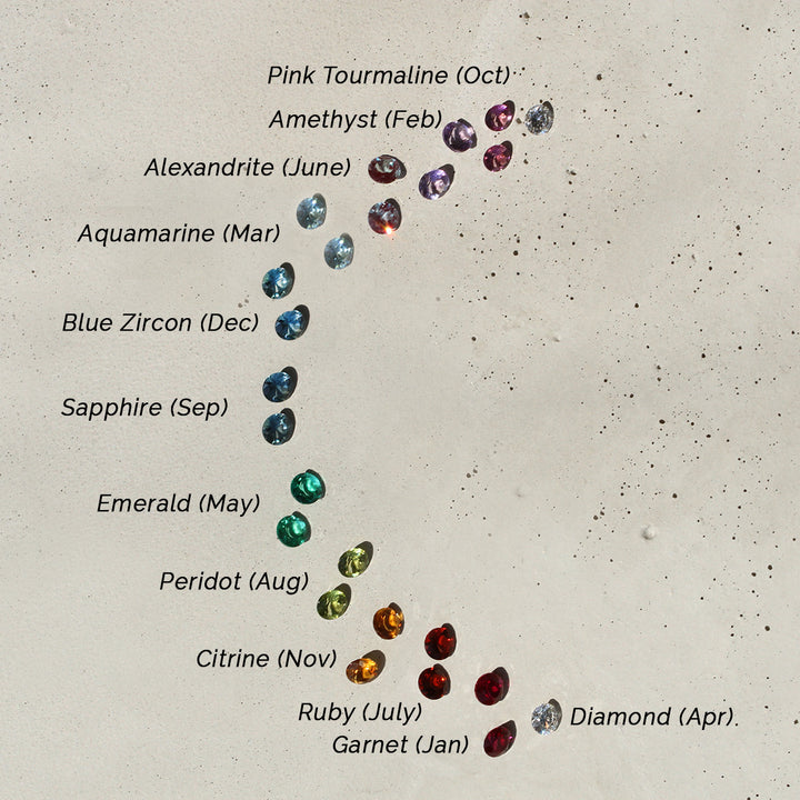 A selection of gemstone studs, each featuring a different colored gemstone, displayed against a neutral background.
