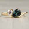 Gold ring with a sapphire gemstone and a diamond on a light gray background