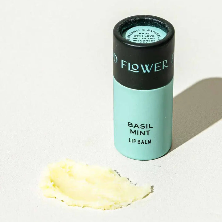Good Flower Farm Basil Mint Lip balm container with a small amount of balm on a white background