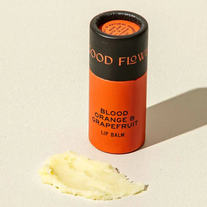 Good Flower Farm Blood Orange & Grapefruit Lip balm container with a small amount of balm on a white background 