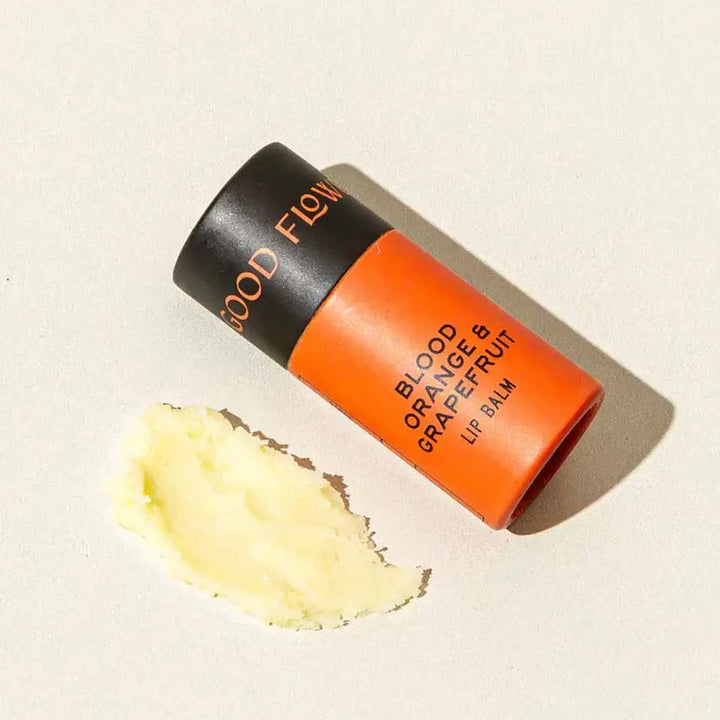 Good Flower Farm Blood Orange & Grapefruit Lip balm container with a small amount of balm on a white background