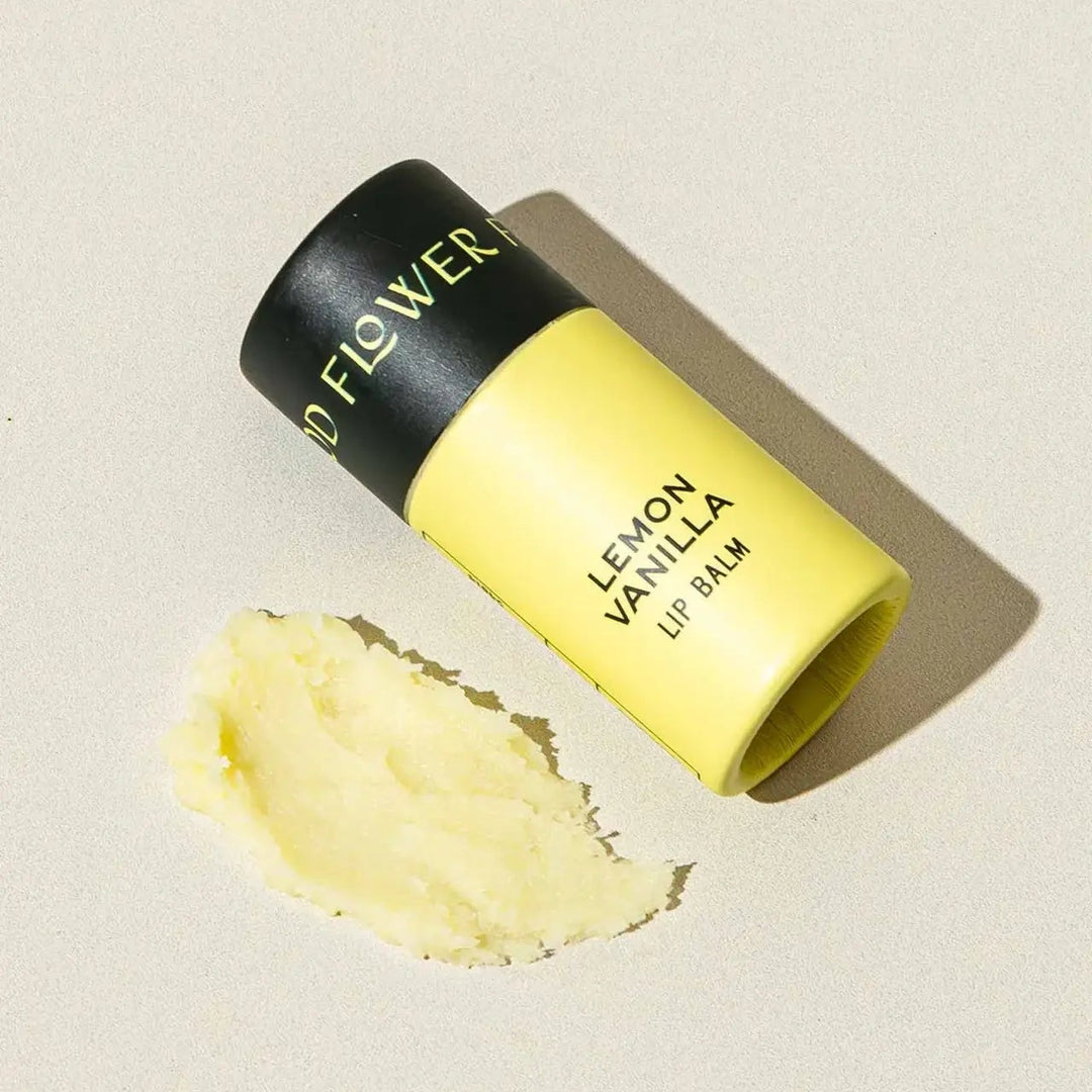 Good Flower Farm Lemon Vanilla Lip balm container with a small amount of balm on a neutral background