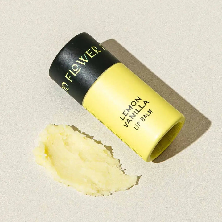 Good Flower Farm Lemon Vanilla Lip balm container with a small amount of balm on a neutral background