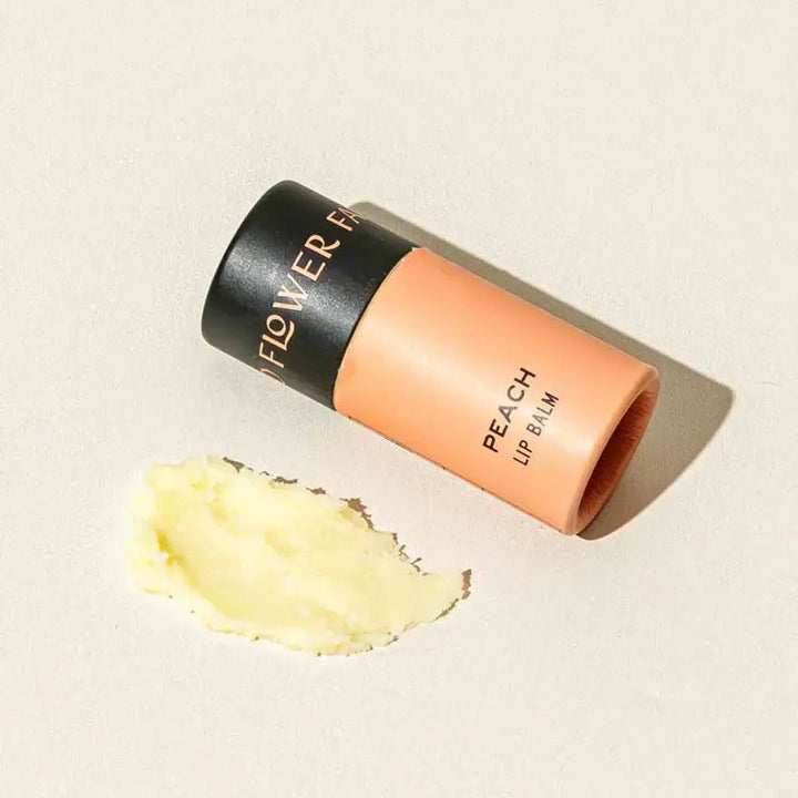 Good Flower Farm Peach Lip balm container with a small amount of balm on a white background