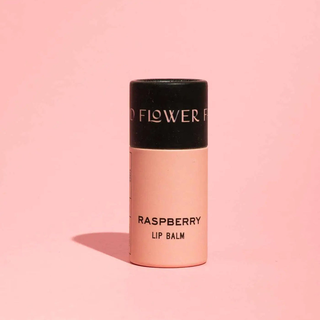 Good Flower Farm Raspberry Lip balm container on a pink background