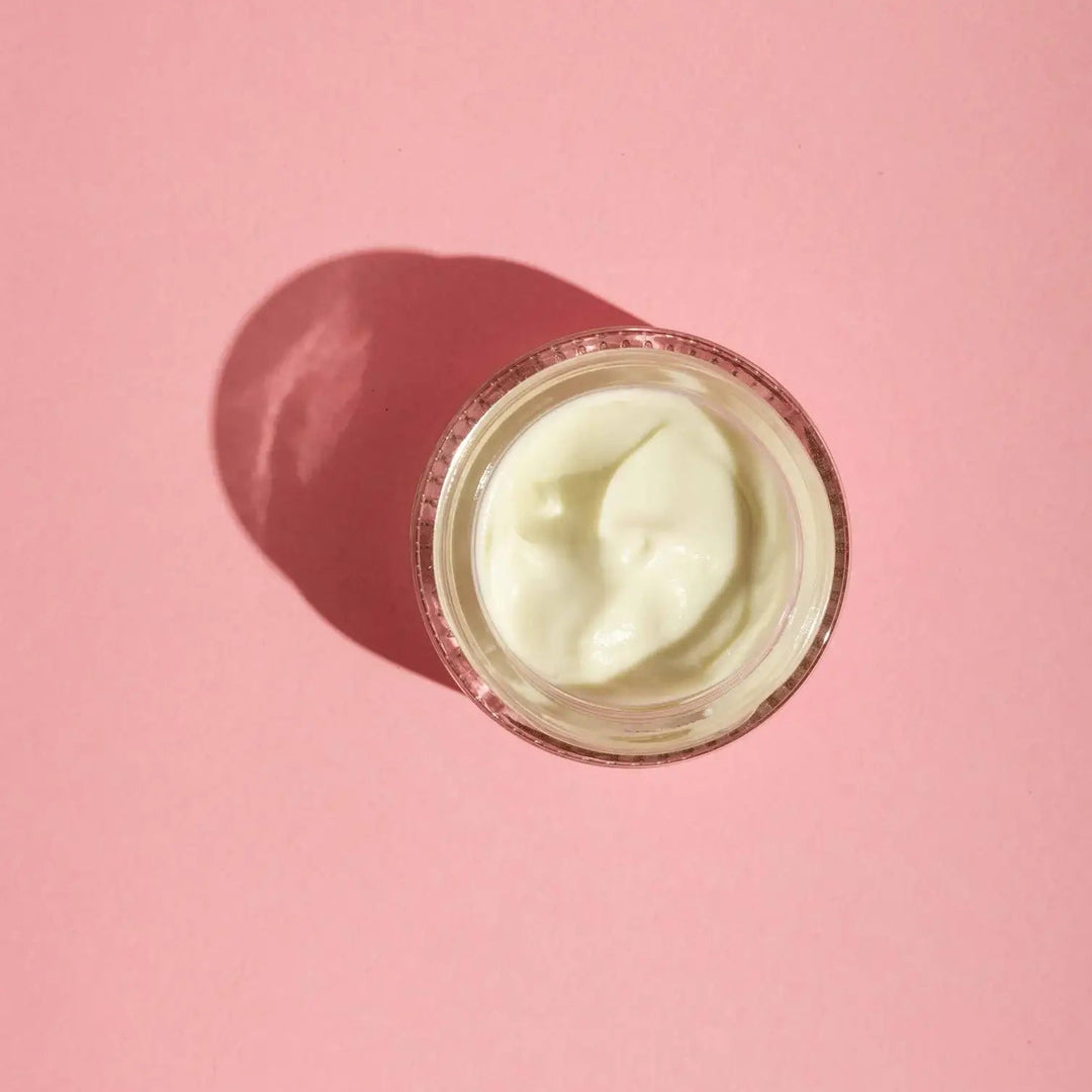 Jar of Good Flower Farm moisturizing Rose Geranium face cream on a pink background