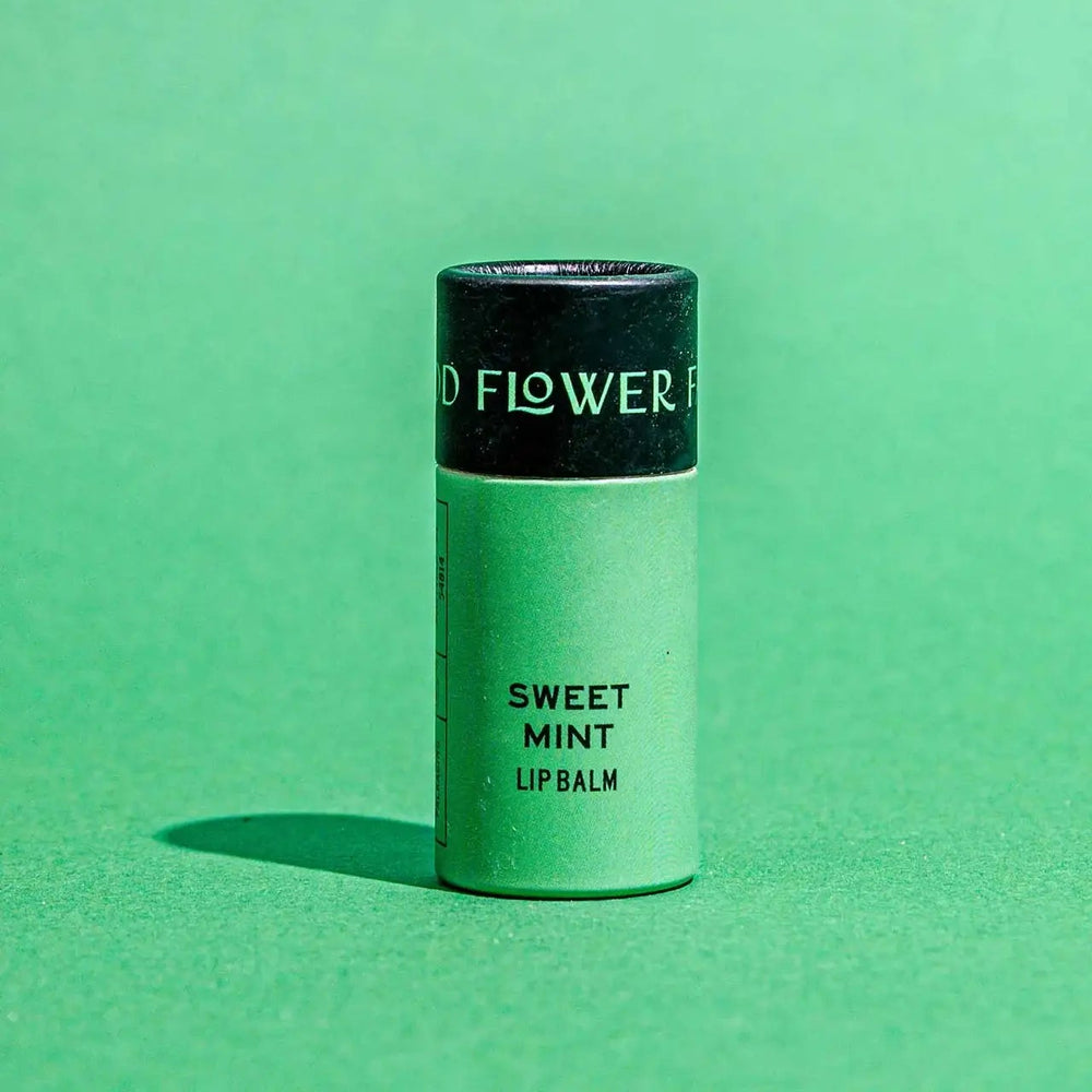Good Flower Farm Sweet Mint Lip balm container on a green background