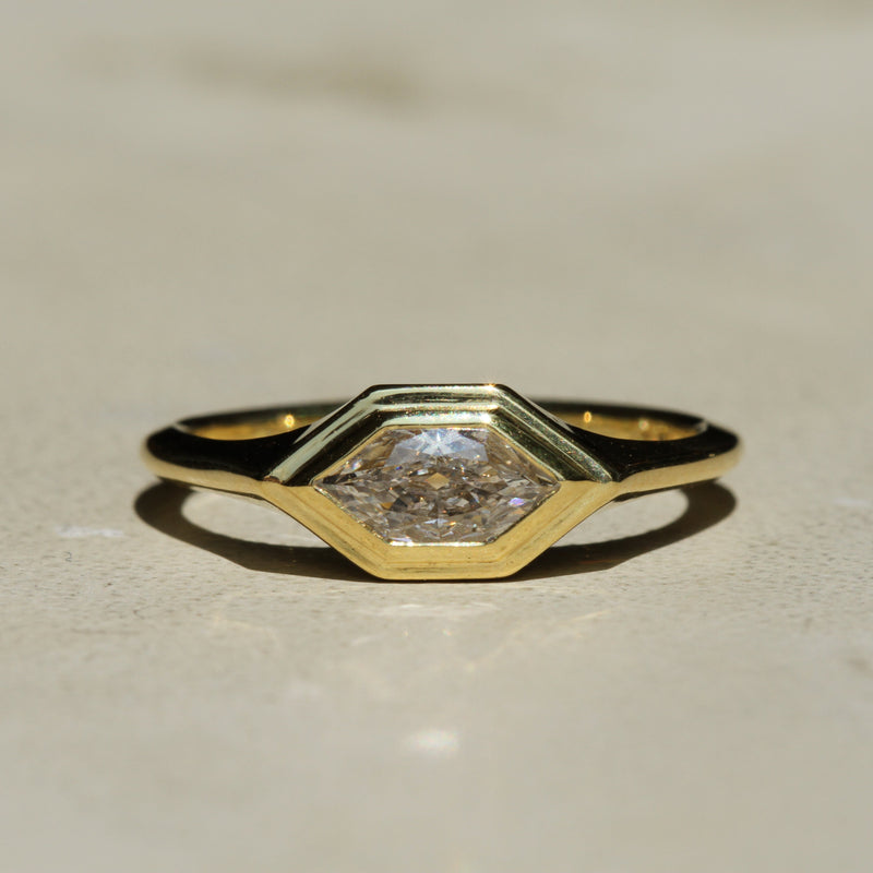 Gold ring with a diamond on a beige background