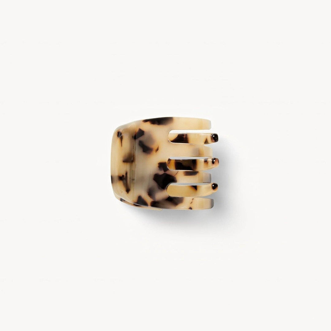 A handcrafted mini claw clip made from Italian bio-acetate in a blonde tortoise pattern, designed to hold hair.