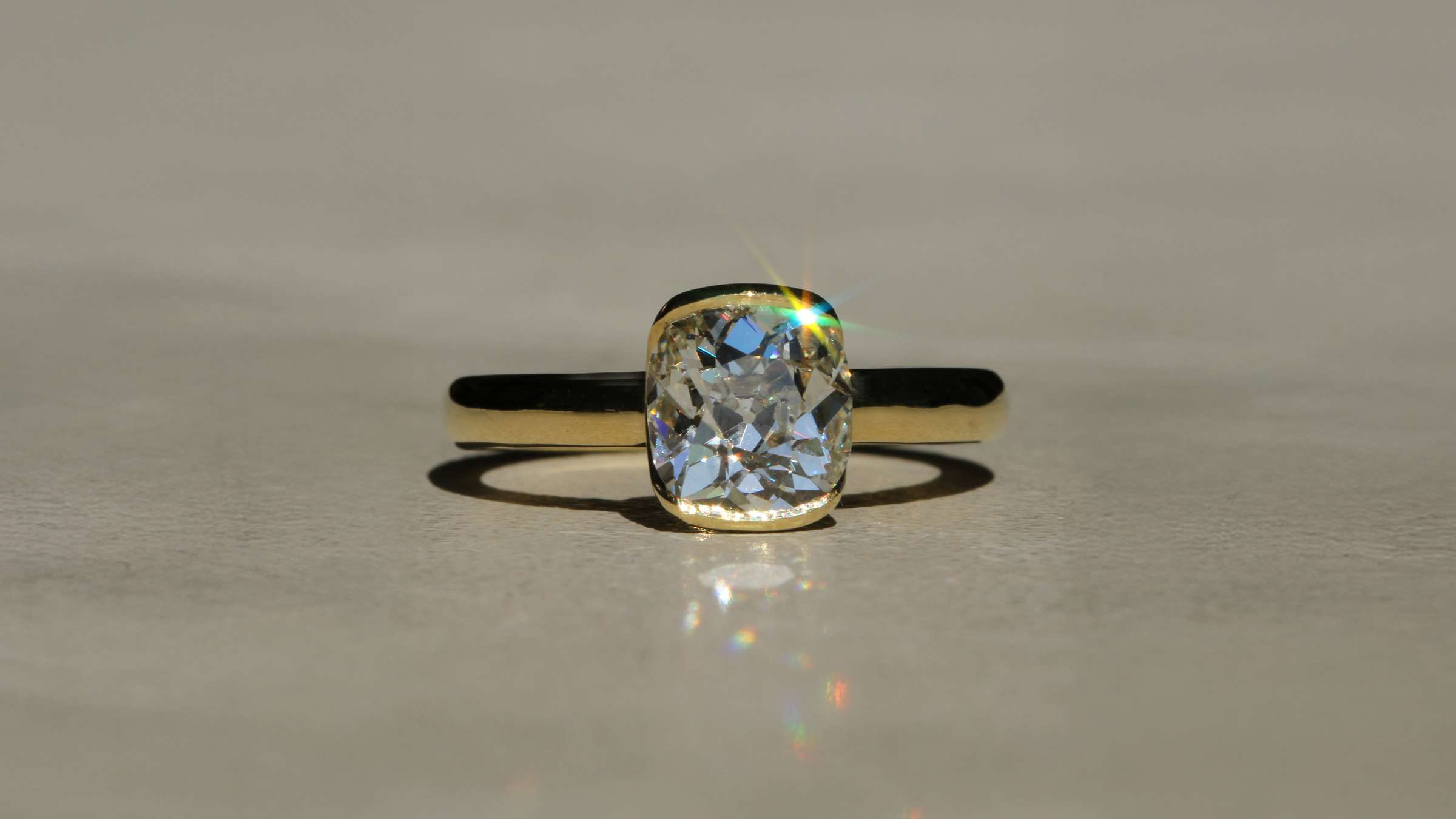 18k Yellow Gold ring with a large OLD MINE diamond on a neutral concrete background