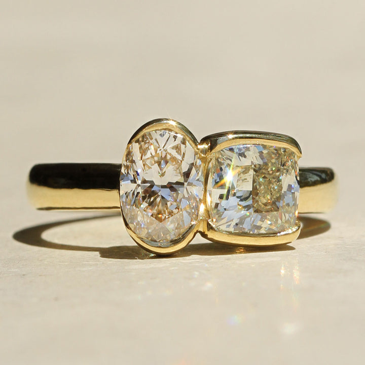 Gold ring with two large diamonds on a beige background
