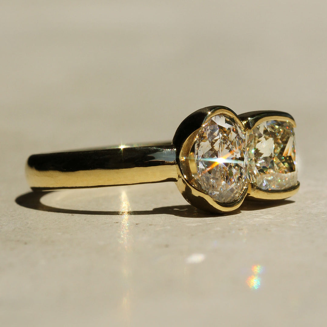 Gold ring with two diamonds on a reflective surface