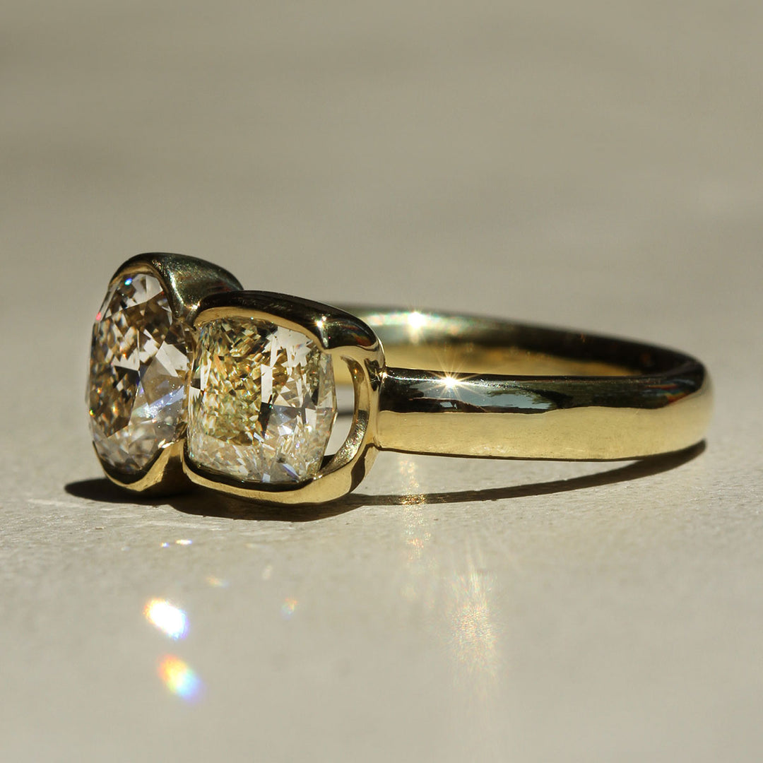 Gold ring with two large diamonds on a reflective surface