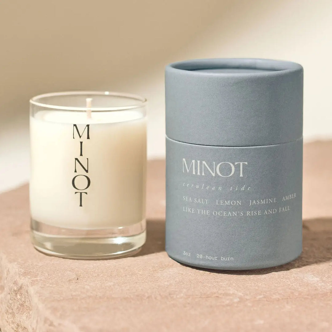 Candle and container with 'MINOT' branding on a beige background