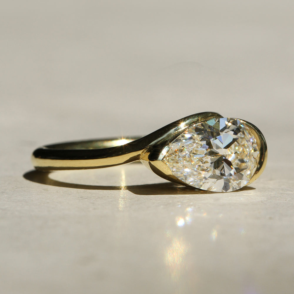 Sophie Hughes Poppy Bezel Wave II Solitaire in 18K Yellow Gold, featuring a 1.5-ct Pear cut diamond, from a slight angle