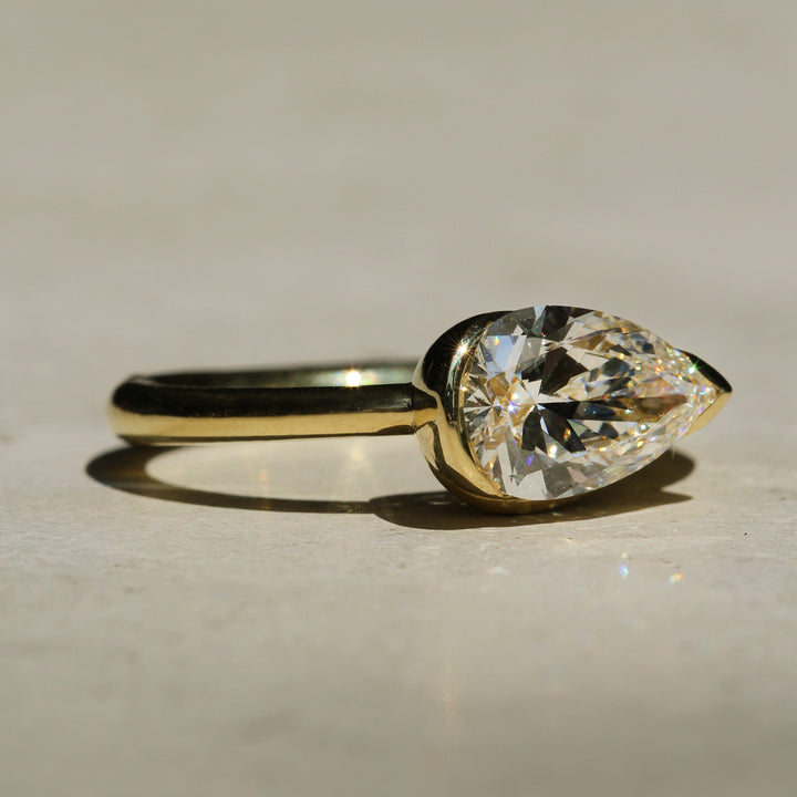 Sophie Hughes Poppy Bezel Wave II Solitaire in 18K Yellow Gold, featuring a 1.5-ct Pear cut diamond, from a slight angle