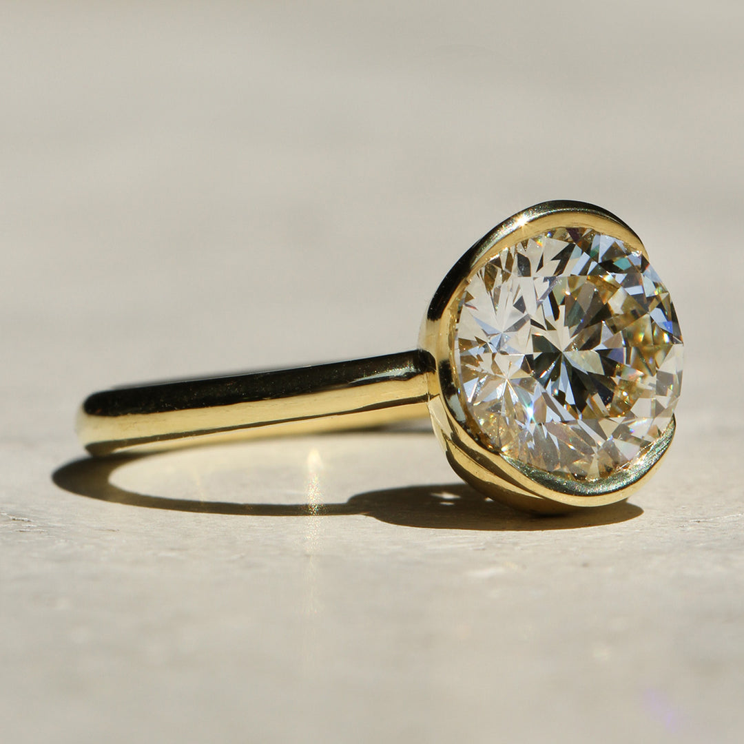 Sophie Hughes Poppy Bezel Wave Solitaire featuring 18K Yellow Gold and a 2-carat Round Brilliant Diamond from a side angle