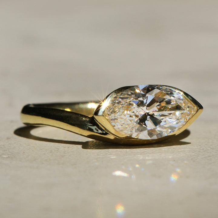 Sophie Hughes Poppy Bezel Cove Solitaire featuring 18K Yellow Gold and a 1.5-carat Marquise Cut Diamond from a slight angle