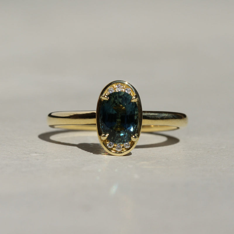 An oval Montana sapphire ring with a halo of white diamonds set in 18k gold, with a comfort fit band.